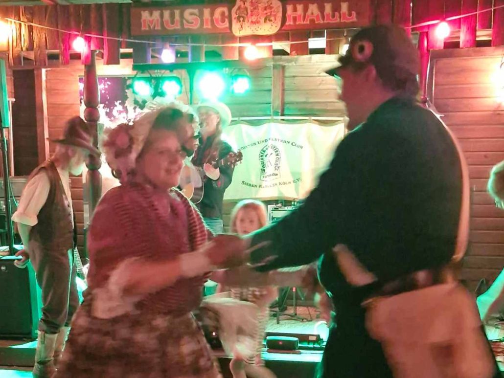 In der Westernstadt tanzen Menschen auf dem Ranchfest.